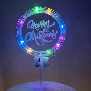 Detail of a glowing Merry Christmas cake topper with colorful LED lights on acrylic