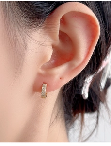 Detail of gold-plated S925 silver hoop earrings with double row paved cubic zirconia on ear