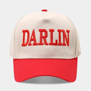 Macro view of red 3D 'DARLIN' embroidery on a beige and red contrast trucker hat