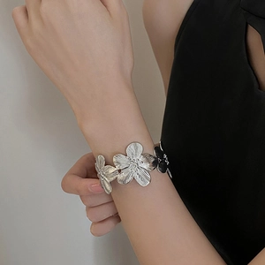 Close-up of vintage silver flower cuff bracelet with detailed petal textures on arm