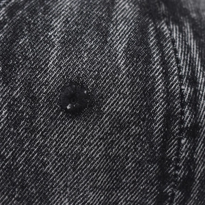 Macro detail of washed denim baseball cap featuring an embroidered eyelet and twill texture