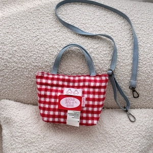 Detail of red and white plaid tote bag with blue denim handles and cherry embroidery