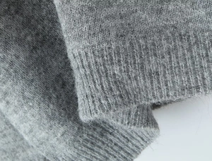 Gros plan du poignet côtelé et de la maille douce de ce pull en laine gris chiné