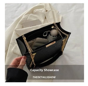 Macro detail of large black quilted tote bag capacity with gold chain and dual straps