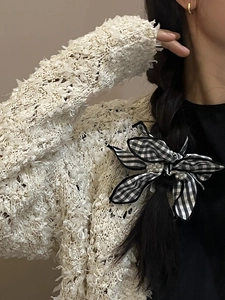 Detail of checkered bow hair tie with white pearls worn on long black hair