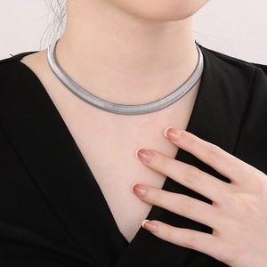 Close-up of minimalist silver snake bone chain necklace on a model showing smooth metallic texture