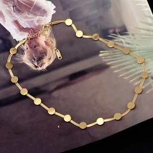 Détail macro d'un collier chaîne serpent en acier titane doré avec petits disques ronds