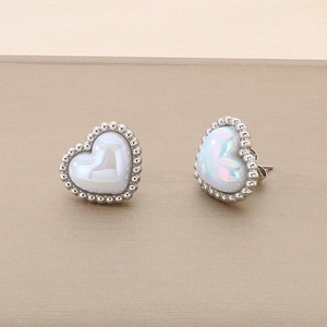 Close-up of heart-shaped shell stud earrings with polished silver bead border details