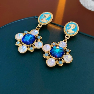Detailed macro view of vintage gold earrings with blue gemstones and embossed portraits