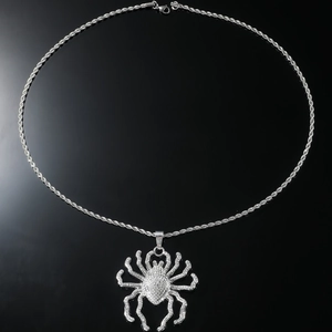 Macro detail of a silver spider pendant with sparkling crystals and a twisted rope chain