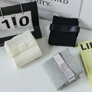 Three pairs of JK mid-tube socks in black, white, and grey with bow tie decorations
