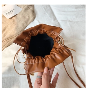 Close-up of brown bucket bag showing drawstring closure and white contrast stitching detail