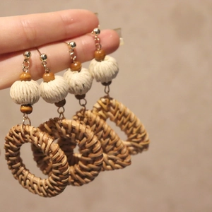 Detailed close-up of Bohemian sun flower earrings with woven rattan and wooden beads