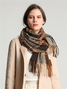Detail of soft brown plaid scarf with fringe tassels shown on a model for winter warmth