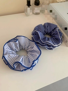 Detailed view of oversized blue and white striped fabric scrunchies in two color patterns