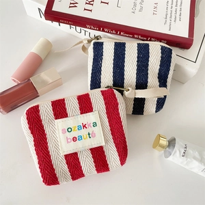 Flat lay of vertical stripe canvas makeup bags with embroidery label and cosmetics