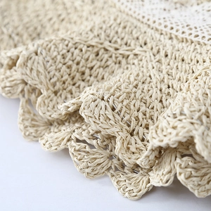 Close-up of the natural beige straw texture and white lace embroidery on a sun hat