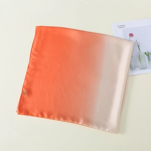 Detailtextur des Seidenschals mit Farbverlauf von Orange zu Beige auf dem Tisch