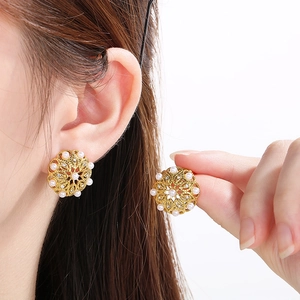 Detailed view of elegant gold flower earrings with pearls and crystals on a model