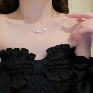 Close-up of a silver zircon flower pendant necklace worn on a black dress