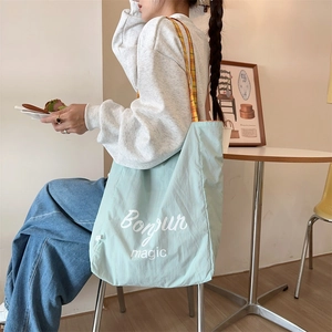 Detail of mint green canvas tote bag with Bonjour magic print in a cafe setting