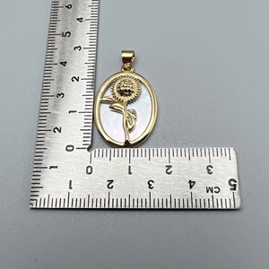 Macro detail of golden sunflower shell pendant showing exact dimensions on a ruler