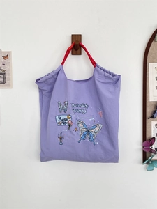 Detail of lavender canvas tote with floral butterfly embroidery and red rope handles