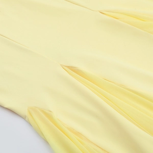 Détail macro du tissu jaune pâle avec plissage complexe et couture en maille filet