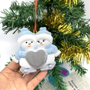 Detail of blue and white snowman ornament with silver heart on a Christmas tree