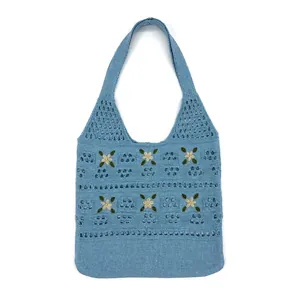 Macro detail of hand-knitted light blue tote with floral embroidery and openwork texture