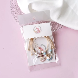 Detail view of woven shell bracelets with faux pearls in transparent OPP packaging