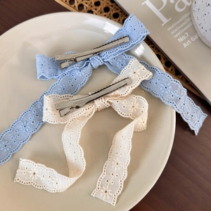 French lace bow hair clips in light blue and cream white on a ceramic plate