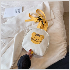 Detail of white canvas toddler backpack with yellow straps and cute tiger patch mascot