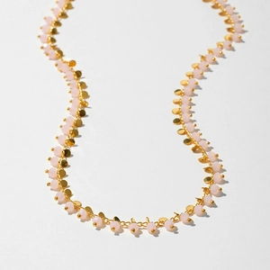 Close-up of pink beads and gold disc pendants on a bohemian choker necklace chain