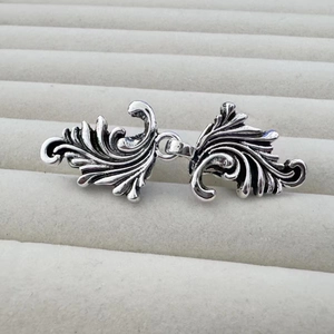 Détail de clips à châle vintage argentés en forme de feuille sur plateau à bijoux gris