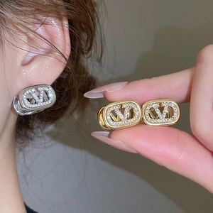 Macro shot of 18k gold plated oval earrings with V-logo and sparkling zircon stones