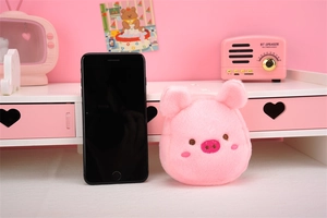 Cute pink plush pig coin purse shown next to a smartphone for size reference
