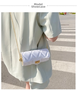 White quilted cylindrical bag with gold chain strap worn over a light green blazer