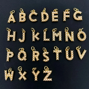 Collection of 26 gold-plated alphabet pendants with elegant pearl inlay on black background