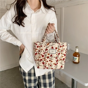 Close-up of floral corduroy tote bag featuring a Pleasant Time label and red flower pattern