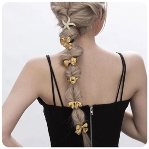 Detail of gold starfish and bow hair accessories on a woman's braided hairstyle