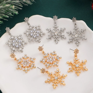 Christmas snowflake stud earrings with sparkling rhinestones and pearls on a green backdrop