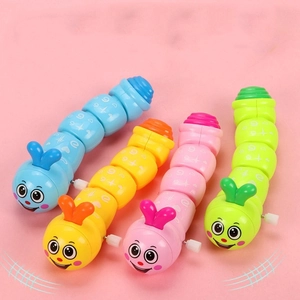 Top view of four colorful plastic clockwork caterpillar toys on a soft pink background