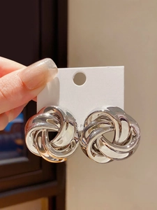Detailed view of silver hollow twisted knot hoop earrings in mirror-polished finish