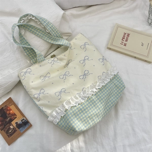 Detailed view of lace trim, plaid patchwork, and bow print on a soft canvas tote bag
