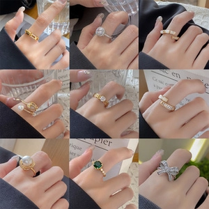 Collage van gouden en zilveren ringen met parels en smaragden aan de vingers