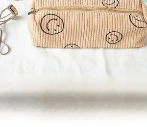 Detail of corduroy makeup bag with smiley faces and metal zipper on white fabric
