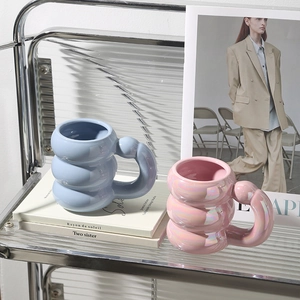 Detail of pink pearlescent and blue bubble ceramic mugs with large round handles