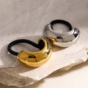 Minimalist gold and silver stainless steel hair ties on a natural stone surface
