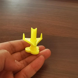 Detail of portable yellow plastic coconut opener tool held over a wooden table